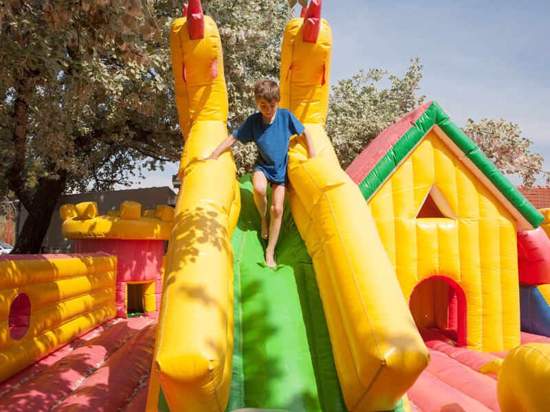 Young Boy Playing In An Inflatable Toy House In A Park